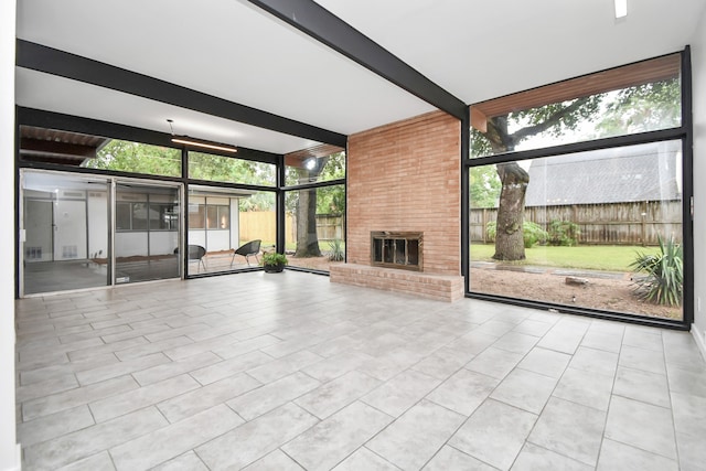 unfurnished sunroom with a wealth of natural light, a fireplace, and beamed ceiling