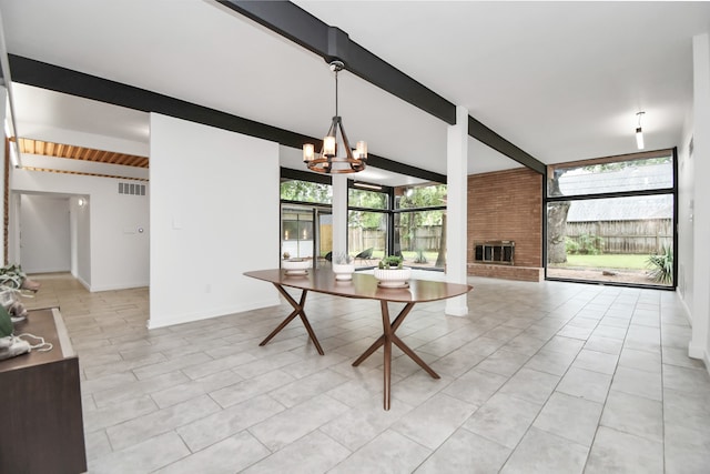 tiled dining space with a brick fireplace, a chandelier, beamed ceiling, and brick wall