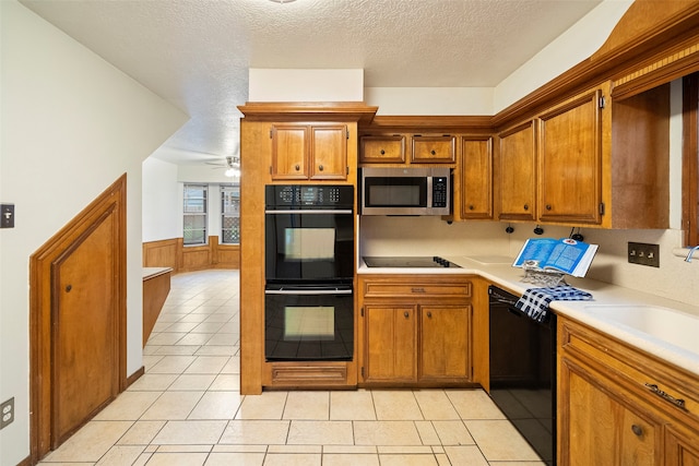 kitchen featuring light tile patterned floors, sink, black appliances, ceiling fan, and a textured ceiling