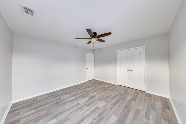 unfurnished bedroom featuring ceiling fan, light wood-type flooring, and a closet