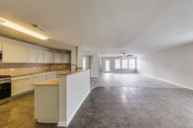 kitchen with ceiling fan, tasteful backsplash, appliances with stainless steel finishes, and dark tile patterned floors