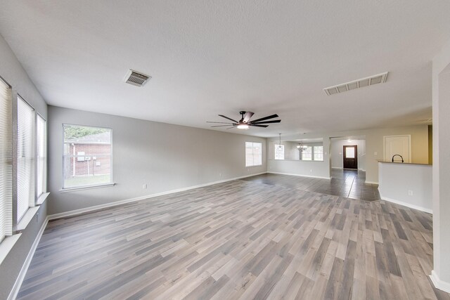 unfurnished living room with ceiling fan and hardwood / wood-style floors