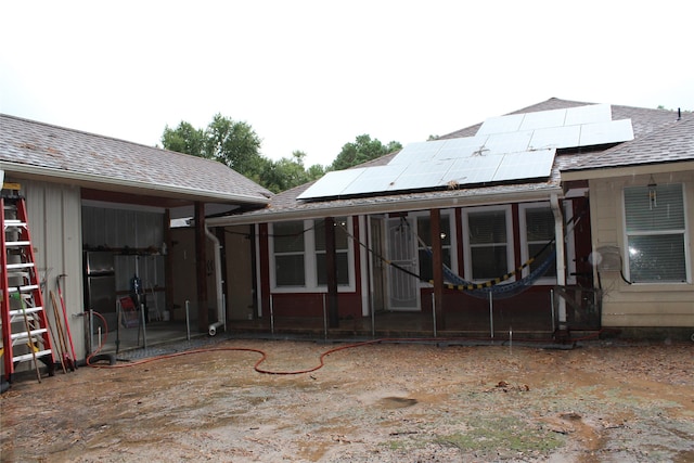 rear view of property featuring solar panels