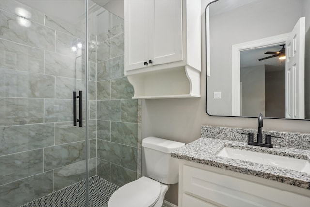 bathroom with vanity, toilet, ceiling fan, and a shower with shower door