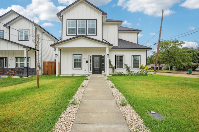 view of front of house featuring a front lawn, fence, board and batten siding, and a shingled roof