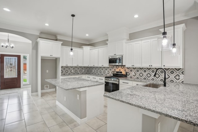 kitchen featuring pendant lighting, tasteful backsplash, stainless steel appliances, sink, and white cabinetry