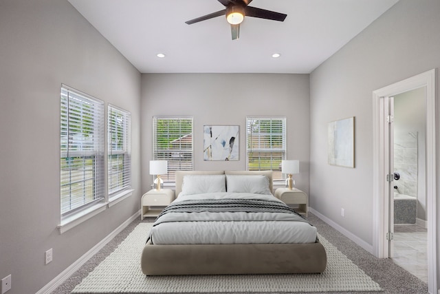 bedroom featuring multiple windows, light colored carpet, ensuite bathroom, and ceiling fan