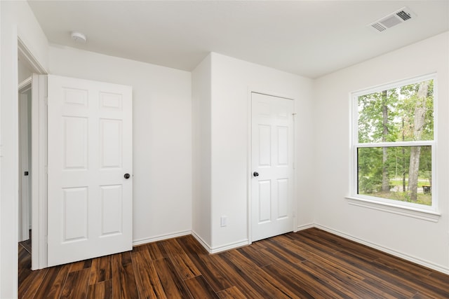 unfurnished bedroom with dark hardwood / wood-style flooring and a closet