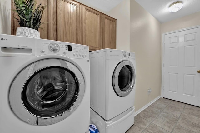 laundry area featuring washing machine and clothes dryer, cabinets, and light tile patterned floors