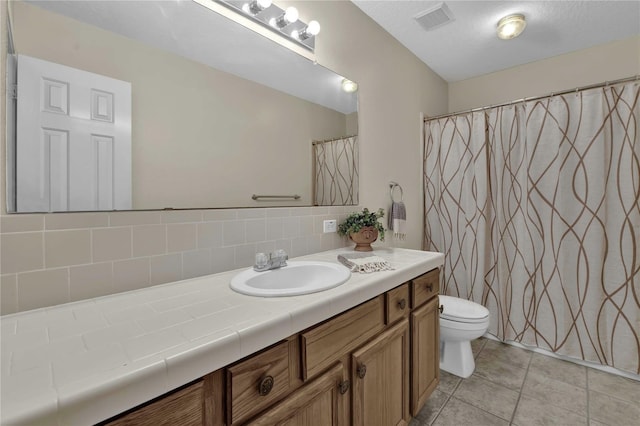 bathroom with tile patterned flooring, tasteful backsplash, toilet, and vanity