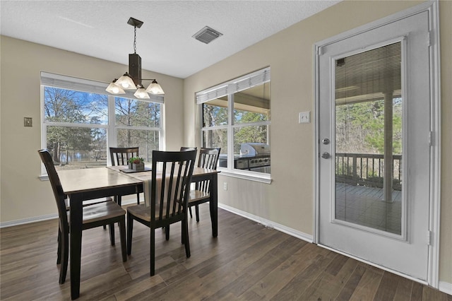 dining space with a notable chandelier, a textured ceiling, and dark hardwood / wood-style floors