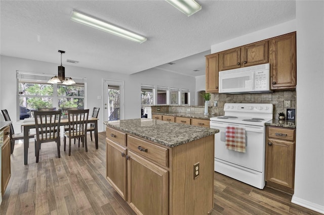 kitchen featuring a center island, white appliances, dark hardwood / wood-style floors, tasteful backsplash, and hanging light fixtures