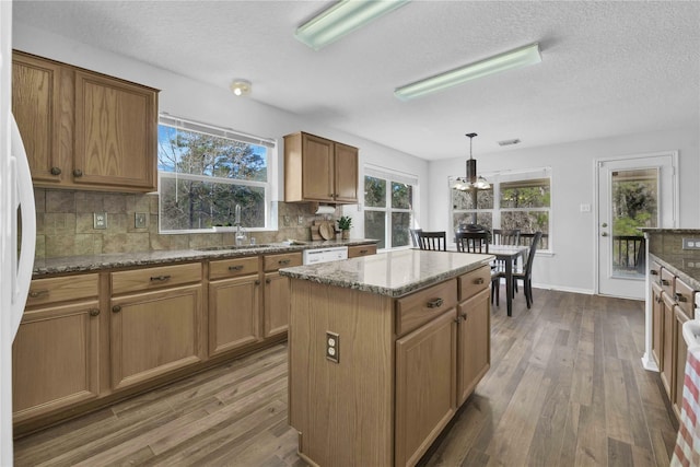 kitchen with sink, hanging light fixtures, hardwood / wood-style flooring, and tasteful backsplash