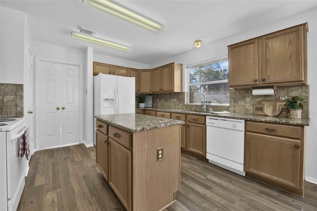 kitchen with a center island, backsplash, dark wood-type flooring, and white appliances