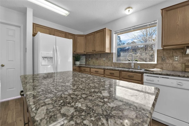 kitchen featuring decorative backsplash, dark hardwood / wood-style floors, stone countertops, sink, and white appliances