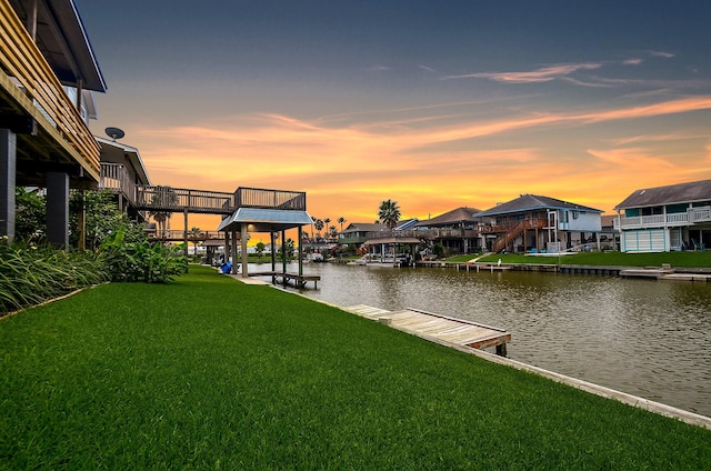 dock area with a residential view, a water view, and a lawn