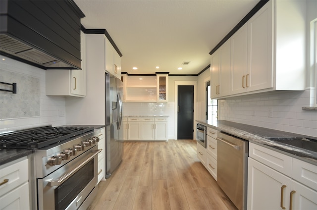 kitchen with decorative backsplash, light wood-style flooring, custom range hood, appliances with stainless steel finishes, and white cabinetry