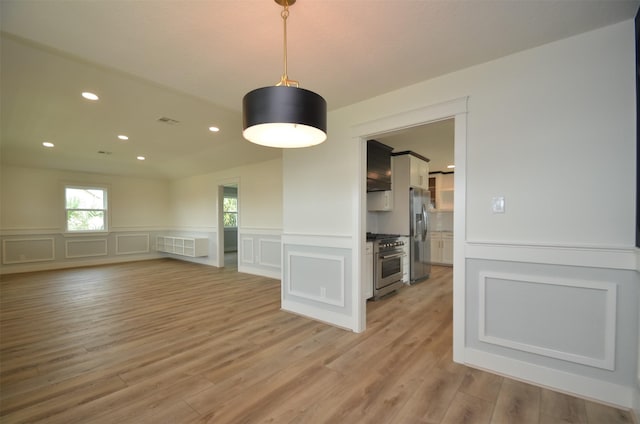 unfurnished room featuring wainscoting, a decorative wall, recessed lighting, and light wood-style floors