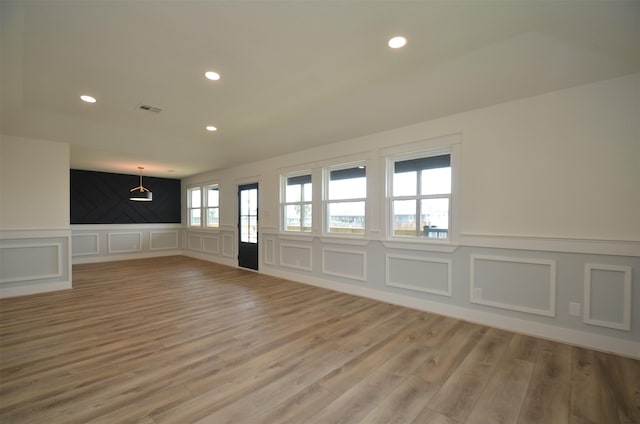 spare room featuring light wood finished floors, visible vents, a decorative wall, and recessed lighting