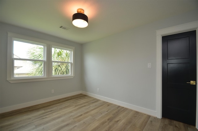 spare room with light wood-style flooring, visible vents, and baseboards