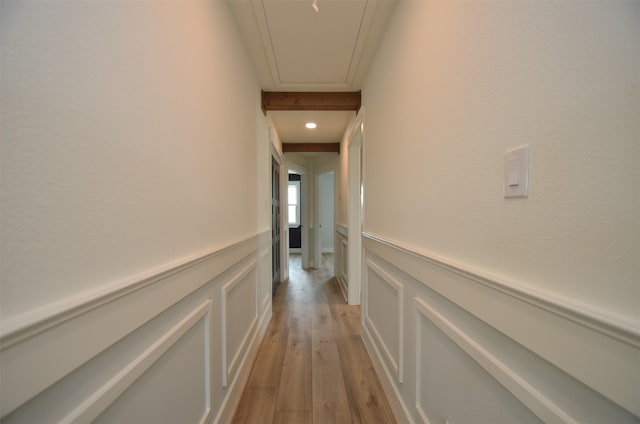 hall featuring a wainscoted wall, attic access, light wood-style flooring, and a decorative wall