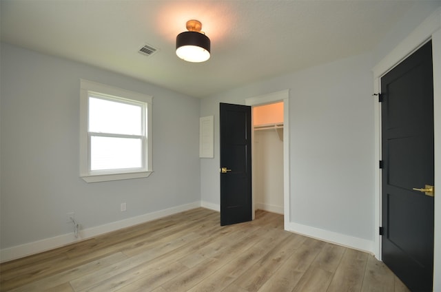 unfurnished bedroom featuring a closet, light wood-type flooring, visible vents, and baseboards