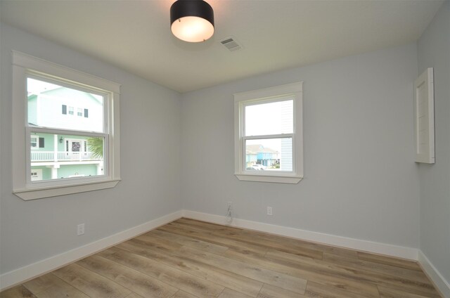 unfurnished room featuring light wood finished floors, baseboards, and visible vents