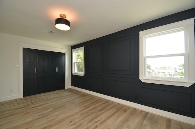 unfurnished bedroom featuring baseboards, a closet, visible vents, and light wood-style floors