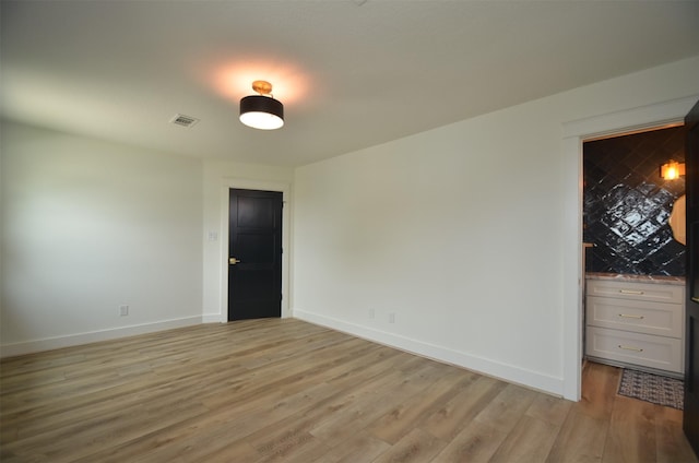 unfurnished room with light wood-type flooring, visible vents, and baseboards