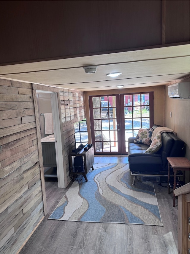 interior space with hardwood / wood-style flooring, wooden walls, a wall mounted air conditioner, and french doors