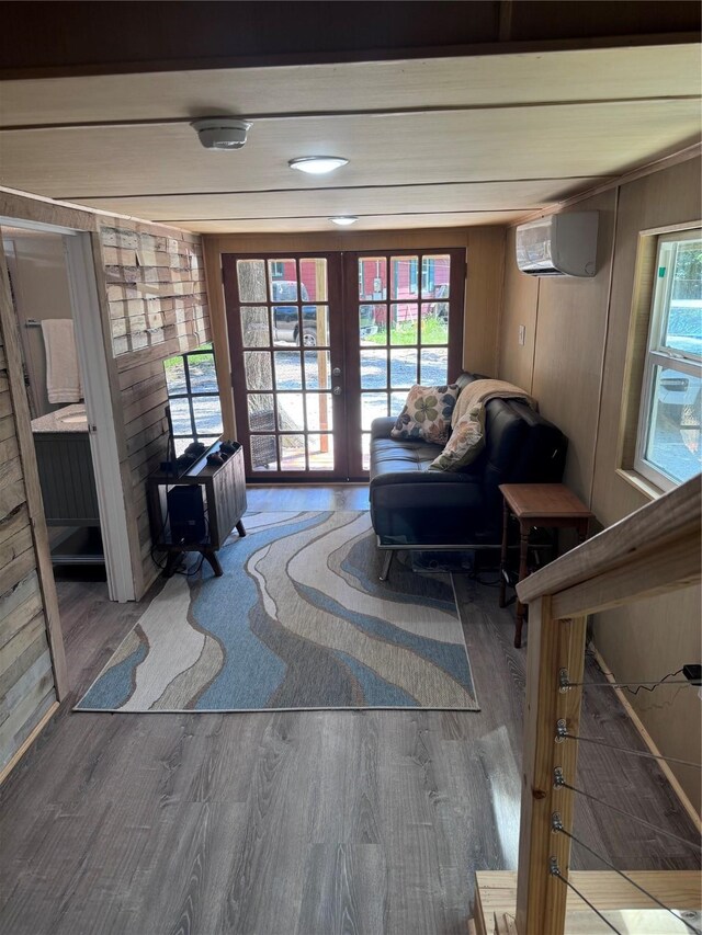 interior space featuring a wall mounted AC, wood-type flooring, plenty of natural light, and french doors