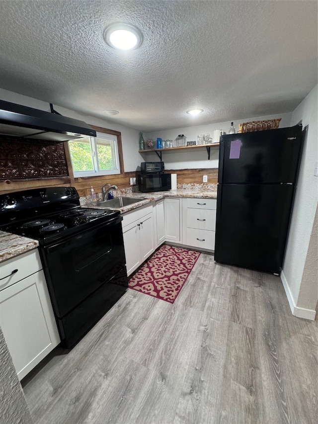 kitchen featuring light wood-type flooring, black appliances, light stone counters, and sink