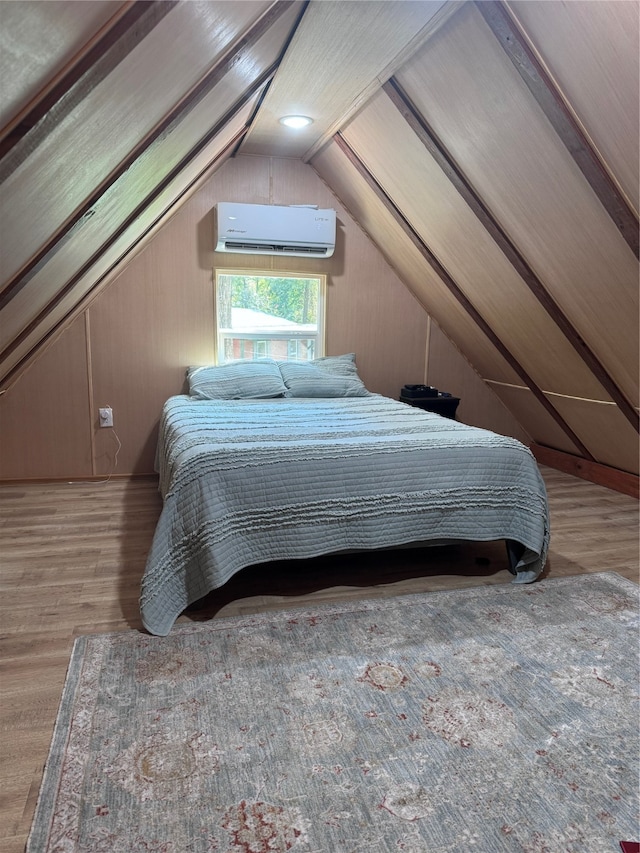 bedroom with lofted ceiling, hardwood / wood-style flooring, and a wall unit AC