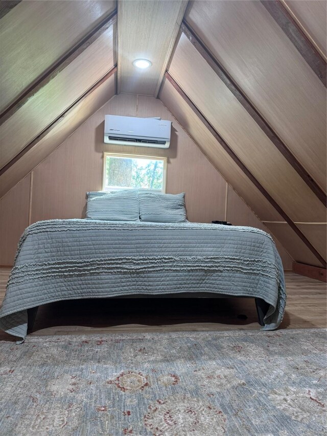 bedroom with vaulted ceiling, hardwood / wood-style floors, and a wall mounted air conditioner