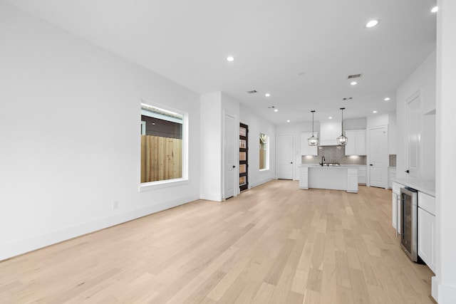 unfurnished living room featuring beverage cooler, recessed lighting, visible vents, and light wood-style floors