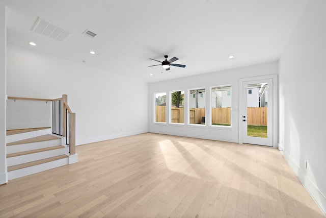 unfurnished living room with light wood-type flooring, visible vents, stairway, and recessed lighting