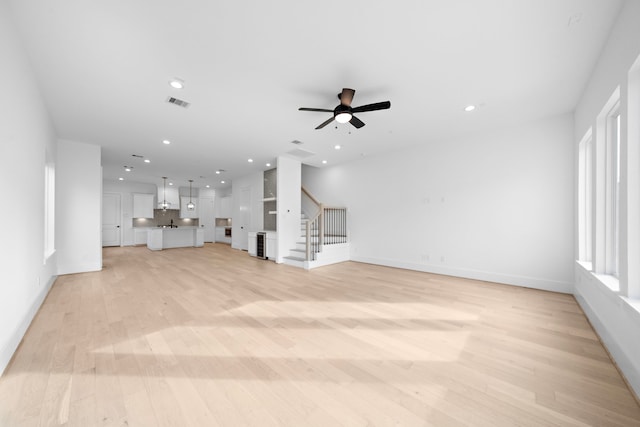 unfurnished living room featuring light wood-type flooring, visible vents, stairway, and recessed lighting