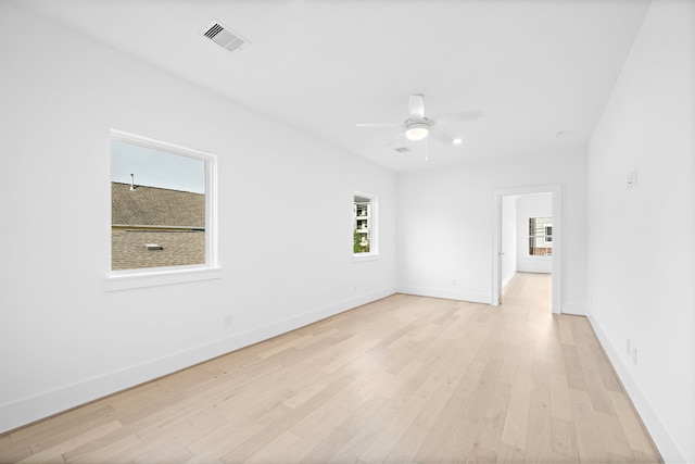 spare room with baseboards, visible vents, ceiling fan, and light wood finished floors