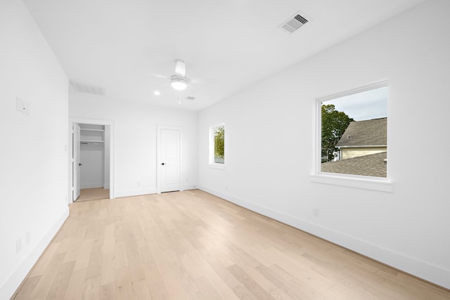 unfurnished bedroom with light wood-style flooring, a ceiling fan, visible vents, and baseboards