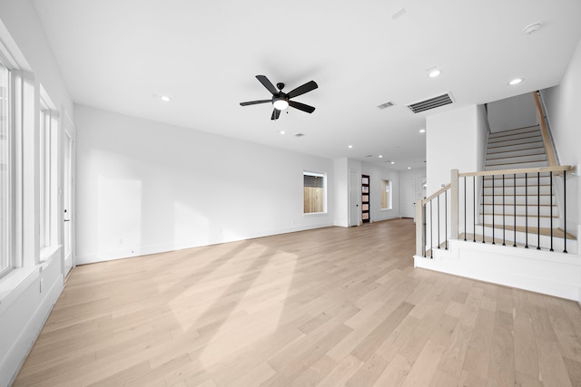 unfurnished living room featuring stairs, light wood finished floors, and visible vents