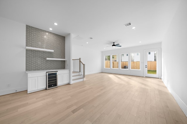 unfurnished living room with wine cooler, recessed lighting, visible vents, light wood-style floors, and baseboards