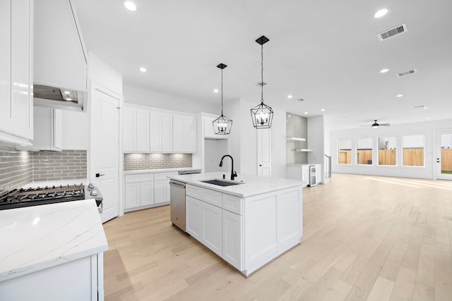 kitchen featuring an island with sink, sink, backsplash, and light hardwood / wood-style floors