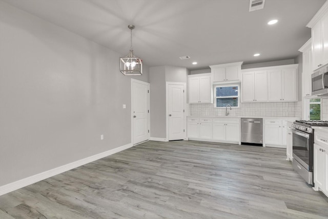 kitchen with sink, light hardwood / wood-style floors, decorative backsplash, white cabinets, and appliances with stainless steel finishes