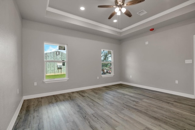 unfurnished room with wood-type flooring, a tray ceiling, ceiling fan, and ornamental molding