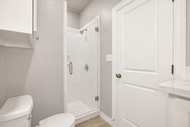 bathroom featuring tile patterned flooring, toilet, and an enclosed shower