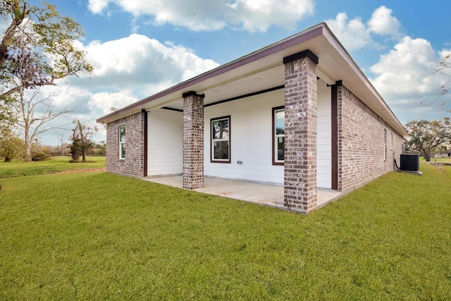 view of side of home featuring central AC unit, a patio area, and a lawn