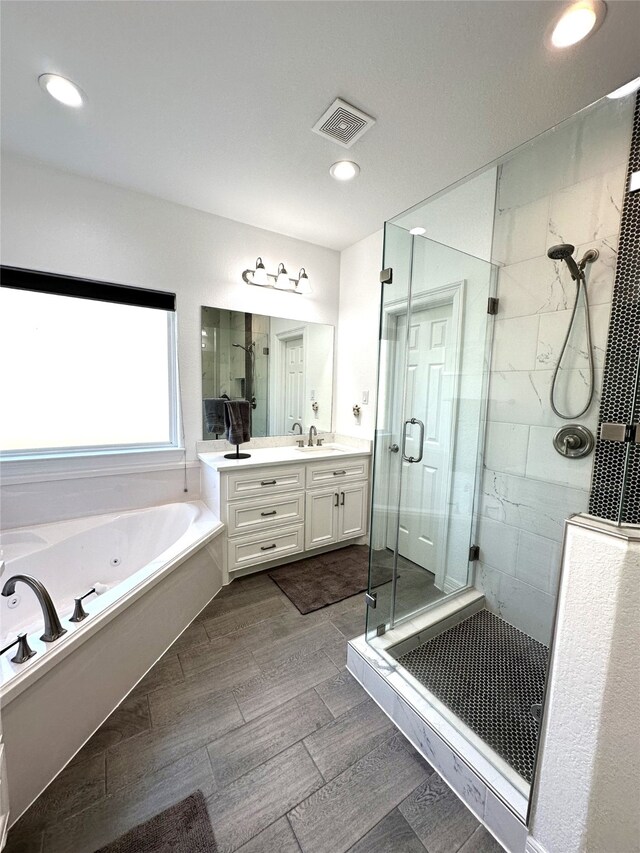 full bathroom with double vanity, visible vents, a jetted tub, a shower stall, and a sink