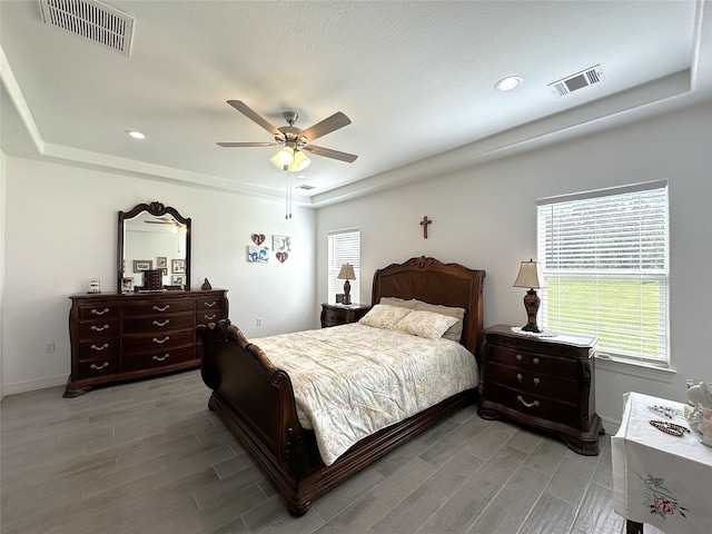 bedroom featuring ceiling fan, hardwood / wood-style floors, and a tray ceiling