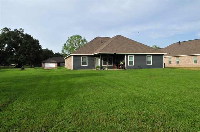 rear view of property featuring roof with shingles and a lawn