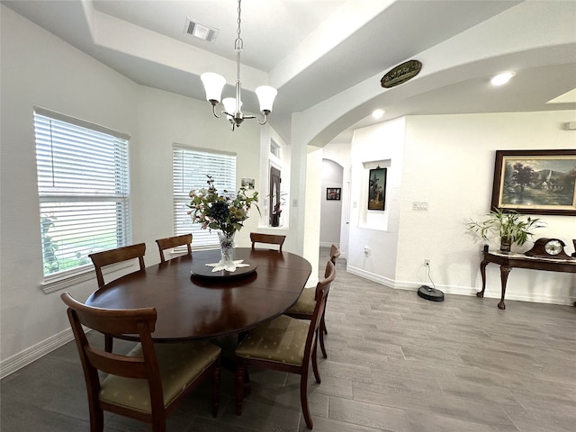 dining room with a notable chandelier, wood-type flooring, and a tray ceiling